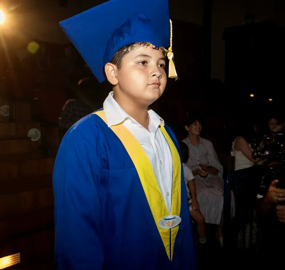 A young boy wearing a blue graduation cap and gown
