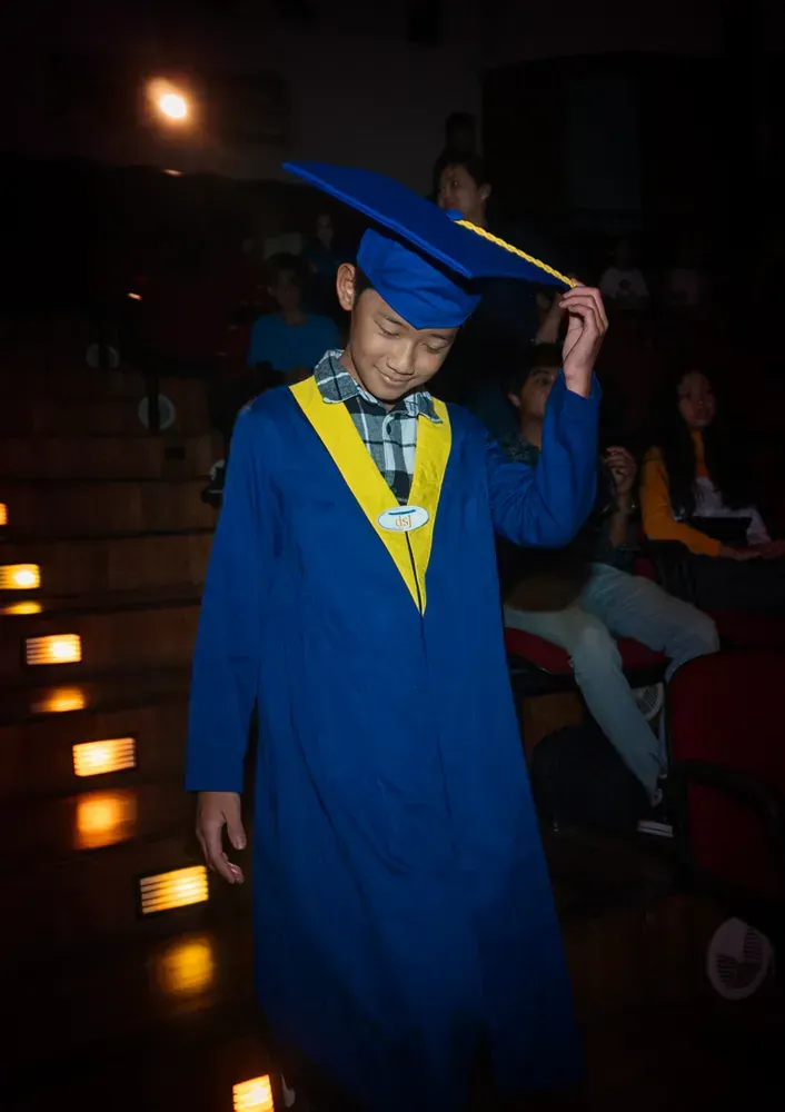 A young boy in a blue graduation cap and gown