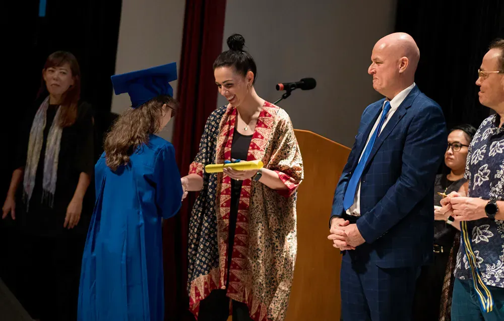 A group of people are standing on a stage at a graduation ceremony.