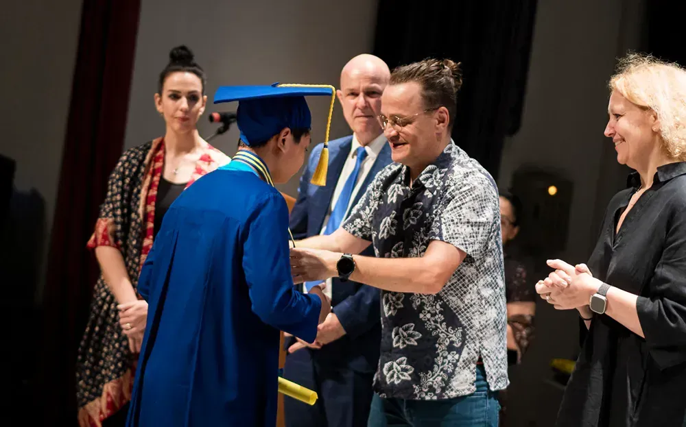 A man is shaking hands with a graduate at a graduation ceremony.