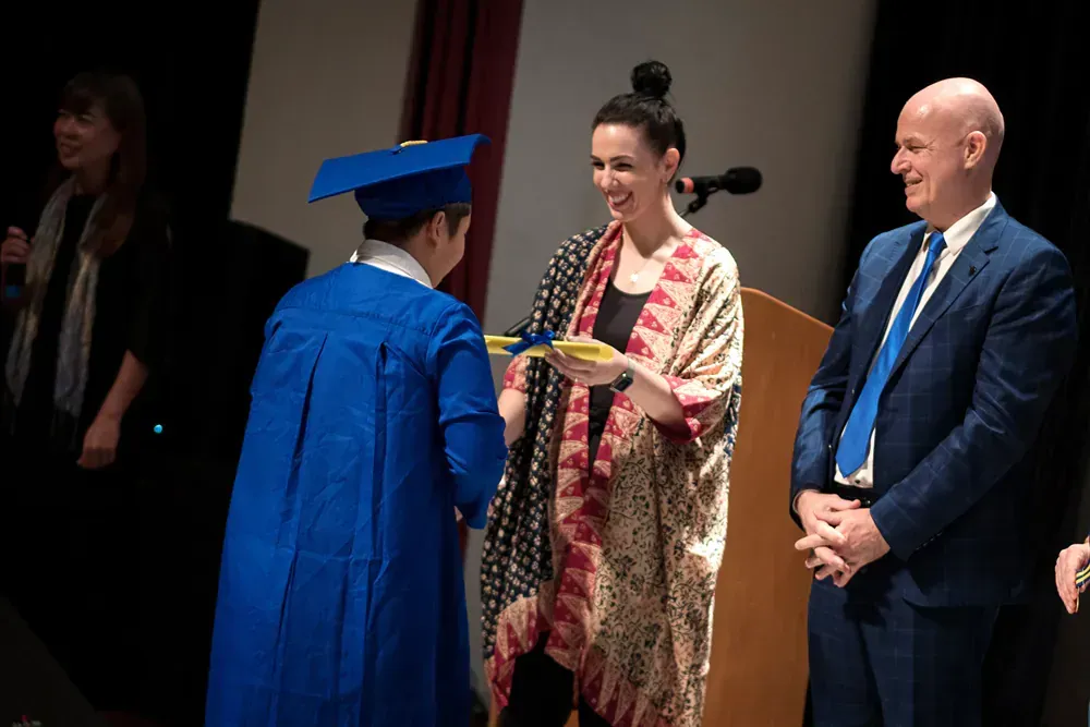 A woman in a graduation cap and gown is standing next to a man in a suit.