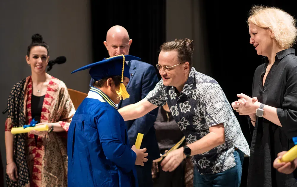 A group of people are standing around a young man in a graduation cap and gown.