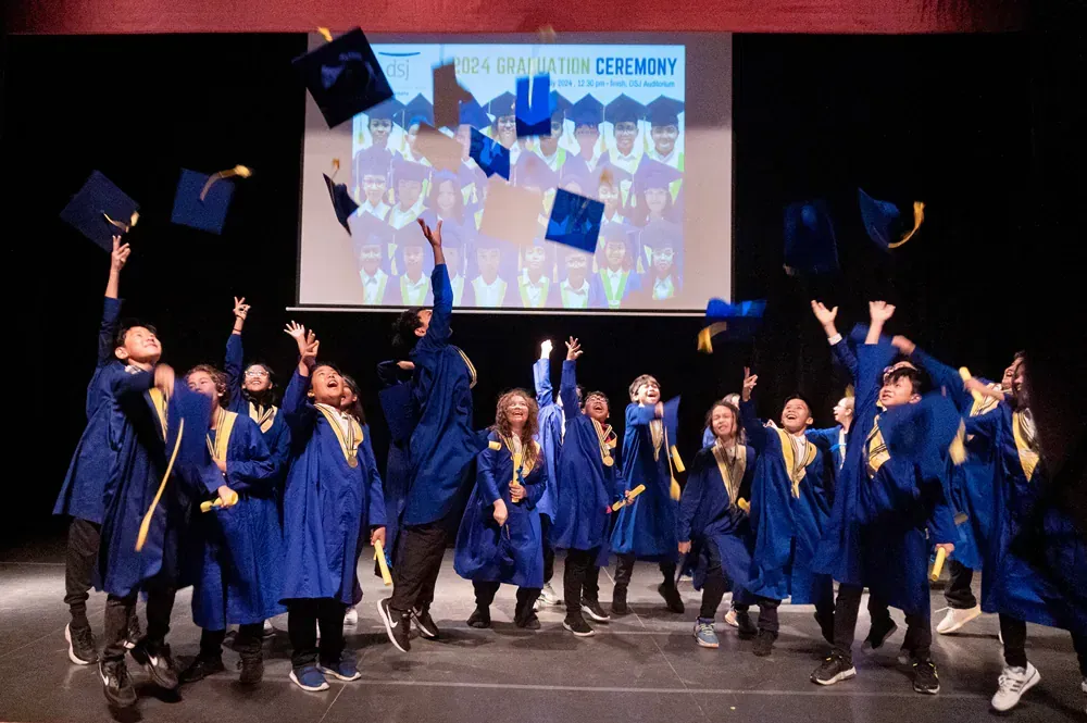 A group of children are throwing their graduation caps in the air.