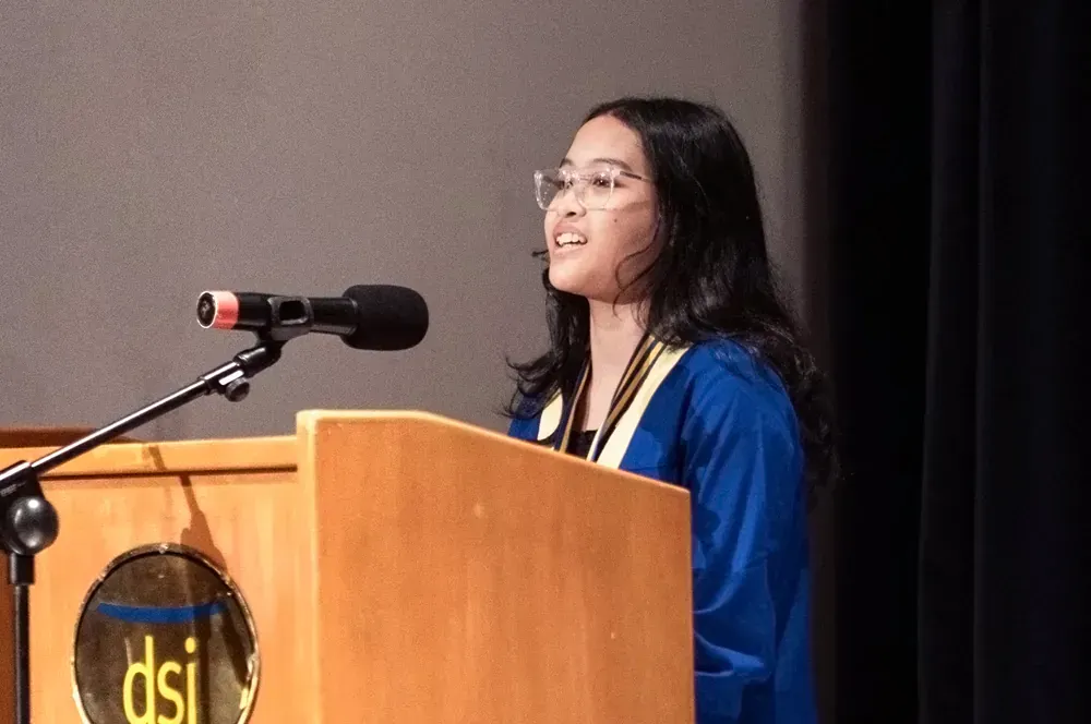A woman is standing at a podium speaking into a microphone.