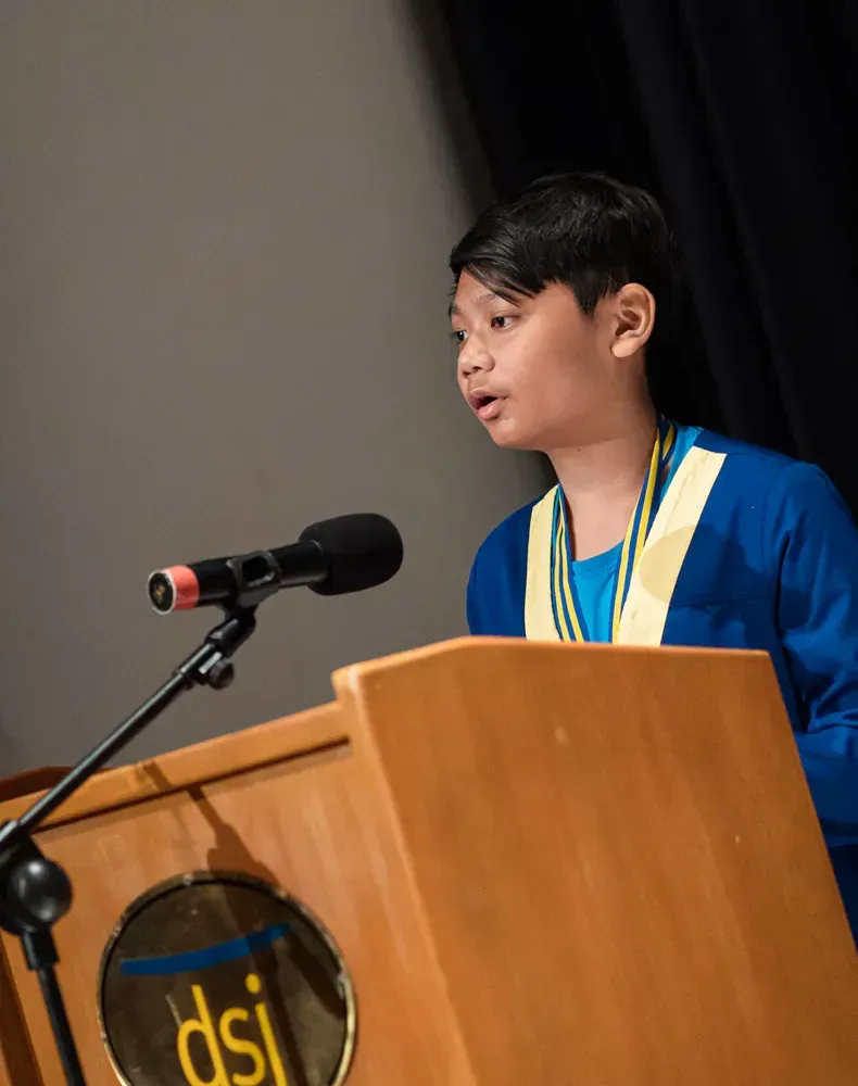 A young boy is giving a speech at a podium that says dsi