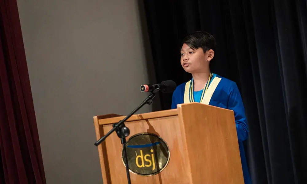 A young boy is standing at a podium giving a speech.