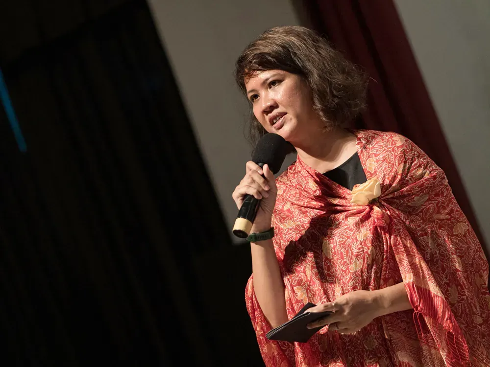 A woman in a red dress is holding a microphone and a tablet.