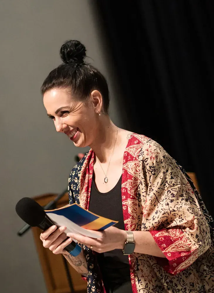 A woman in a kimono is holding a microphone and a book.