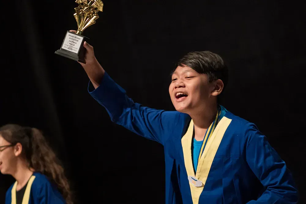 A young boy is holding a trophy in his hand.