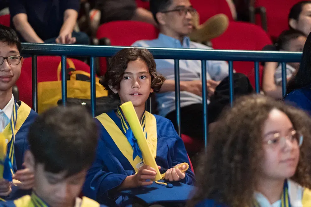 A group of people in graduation gowns are sitting in a auditorium.