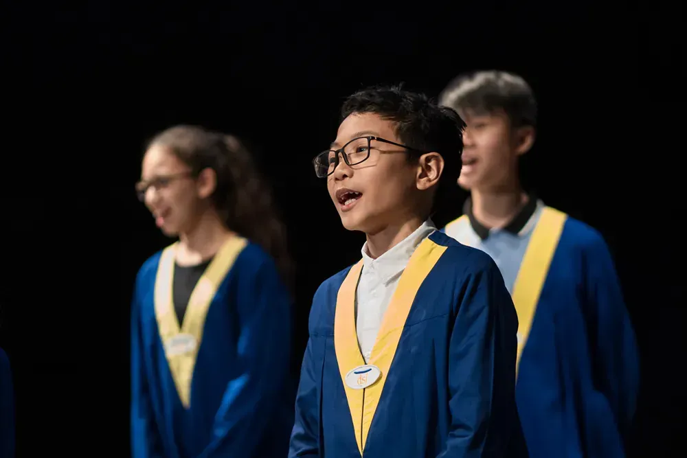 A group of children are singing in a choir on a stage.