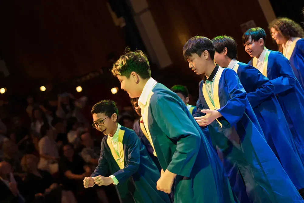A group of young men in graduation gowns are standing on a stage.