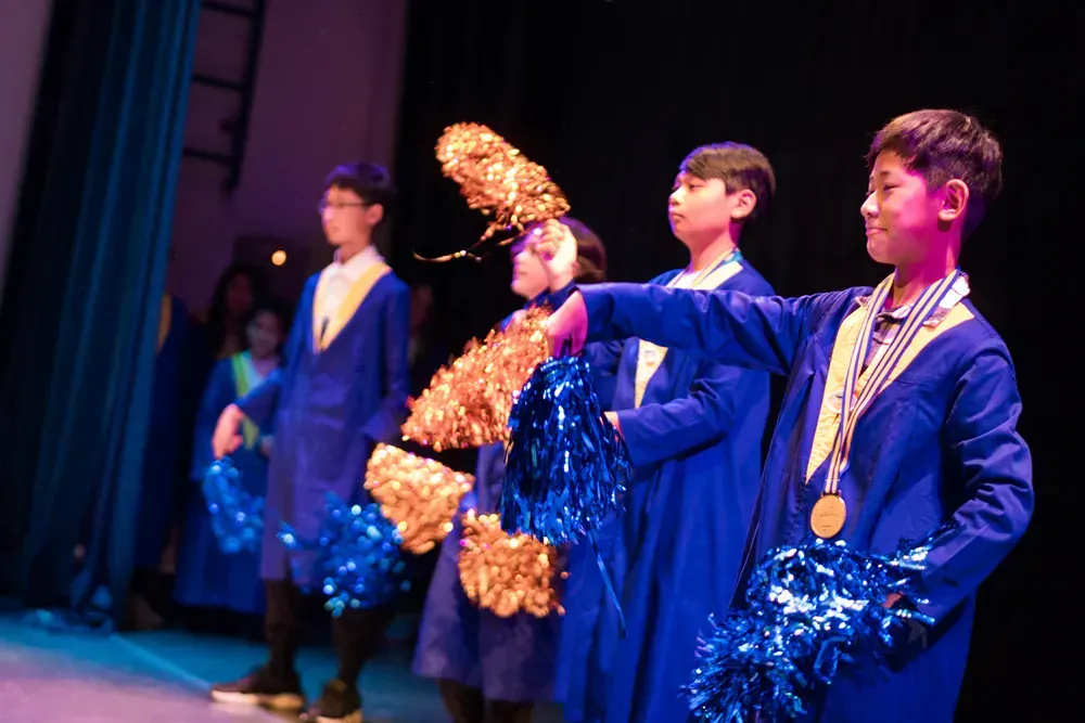 A group of cheerleaders are standing on a stage holding pom poms.