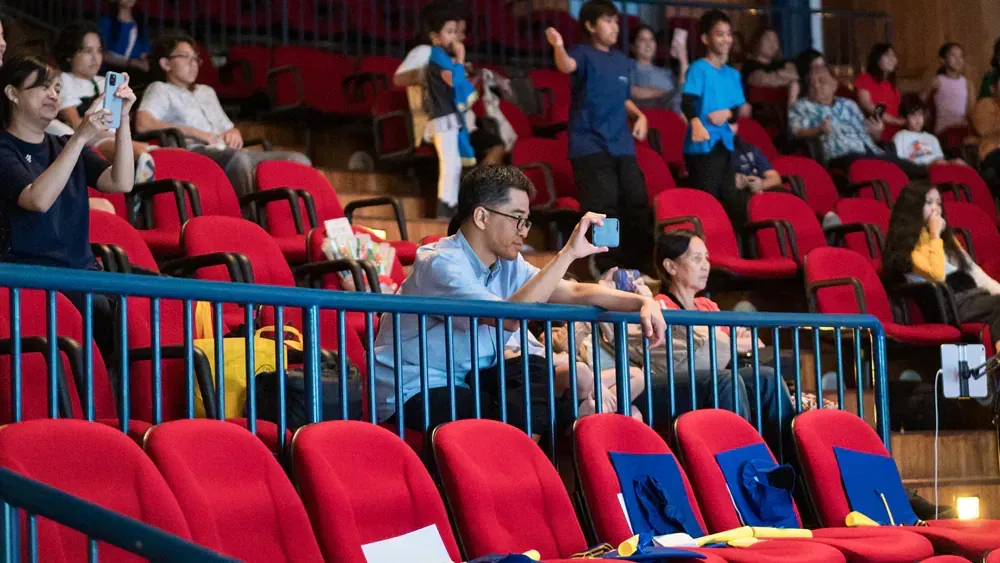 A man is taking a picture of a crowd of people in an auditorium.