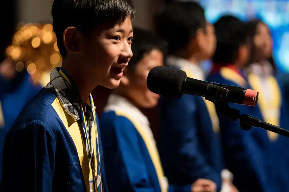 A young boy is standing in front of a microphone.