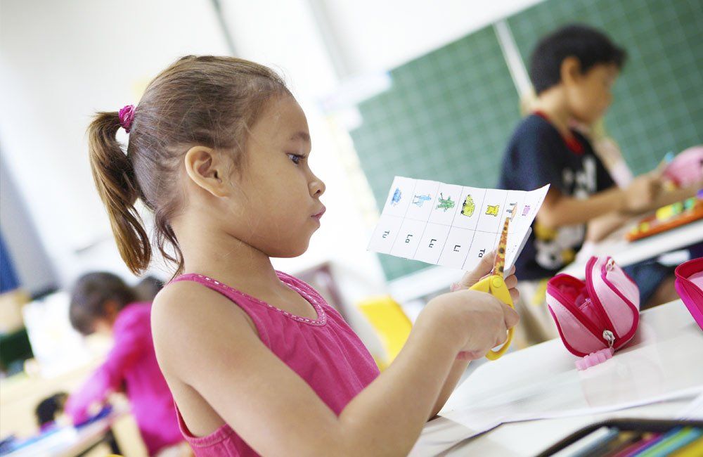 A girl student cutting paper during primary class at the German School Jakarta