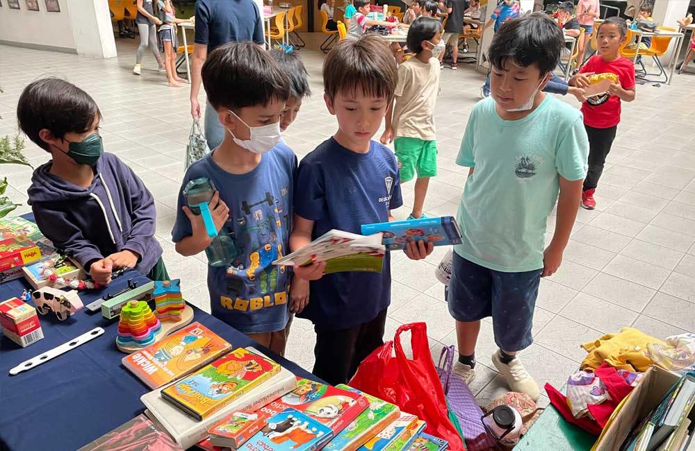A group of young boys are standing around a table looking at books.