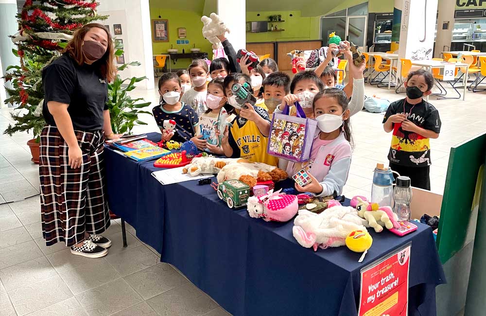 A group of children wearing face masks are standing around a table.