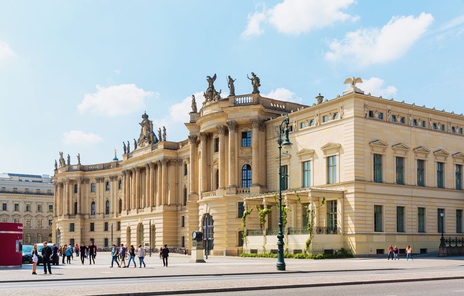 A group of people are walking in front of a large building.