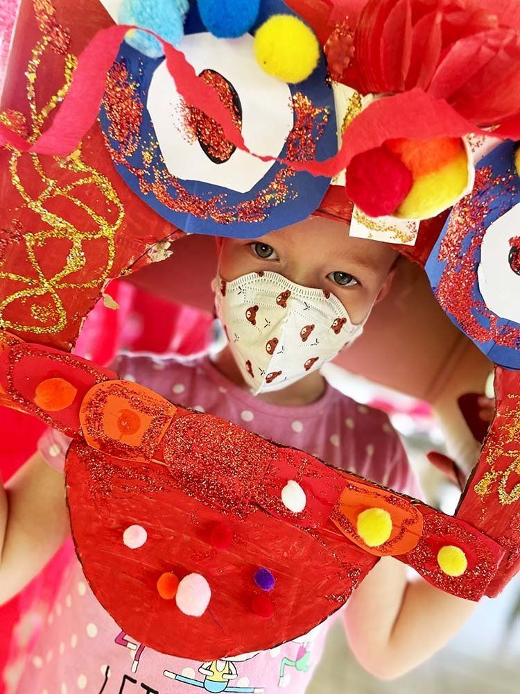 A little girl wearing a mask is looking through a mirror.
