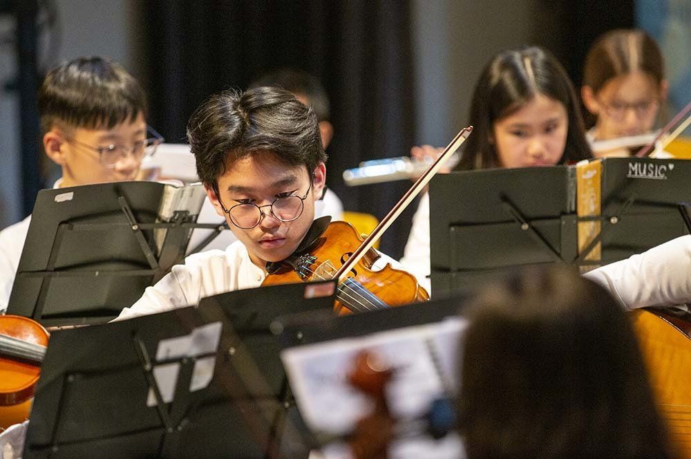 A group of young people are playing violins in an orchestra.