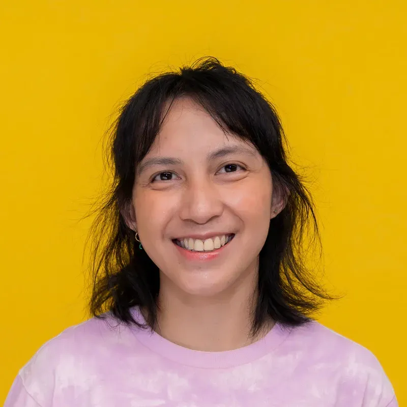 A woman with short hair is smiling and wearing a blue and white shirt.