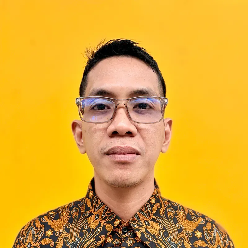 A man in a white shirt is standing in front of a blue background.