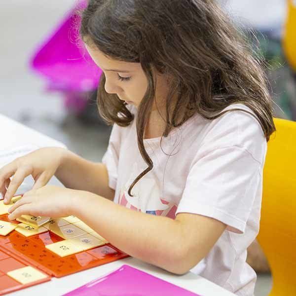 A little girl is sitting at a table playing a game