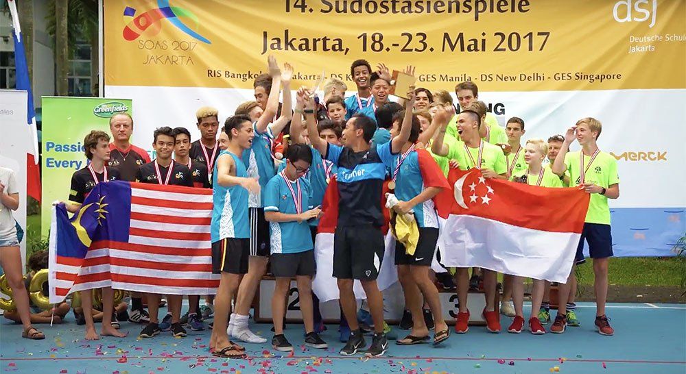 A group of young men are standing on a podium holding flags and medals.
