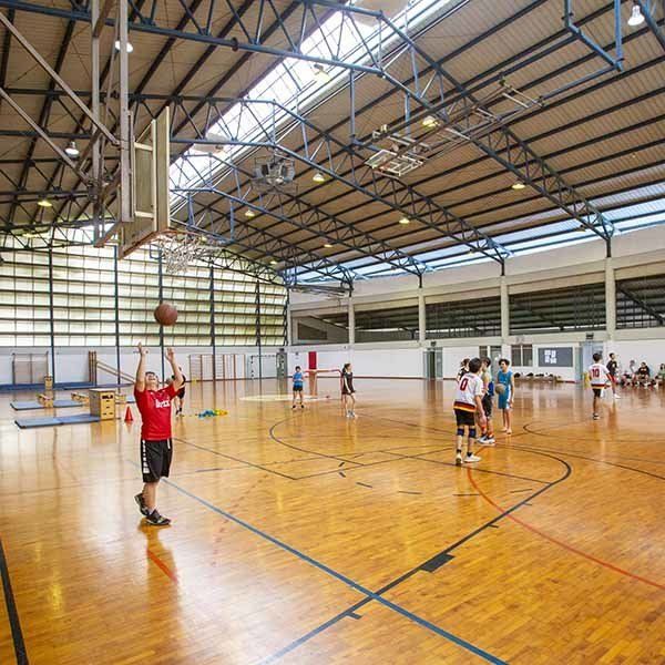 A group of people are playing basketball in a large gym.