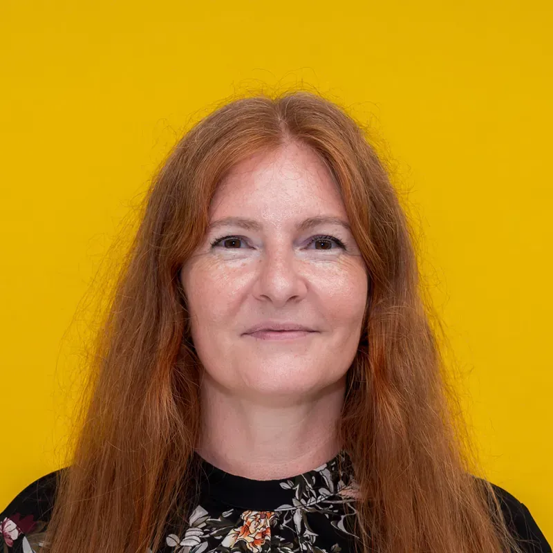 A woman in a blue striped shirt is smiling for the camera.
