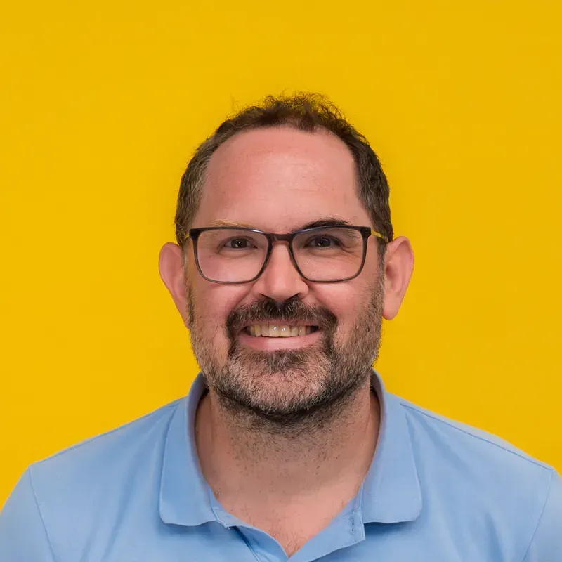 A man with glasses and a beard is smiling for the camera.