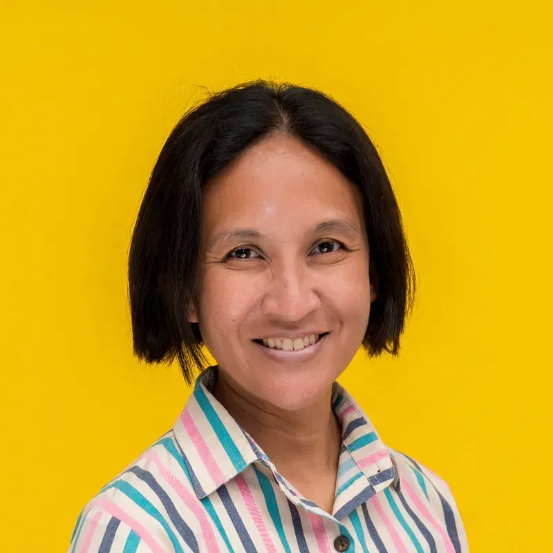 A woman in a red plaid shirt is smiling for the camera.