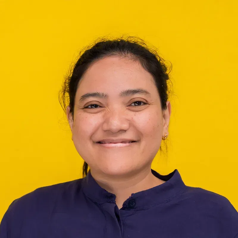 A woman wearing a blue polka dot shirt is smiling for the camera.