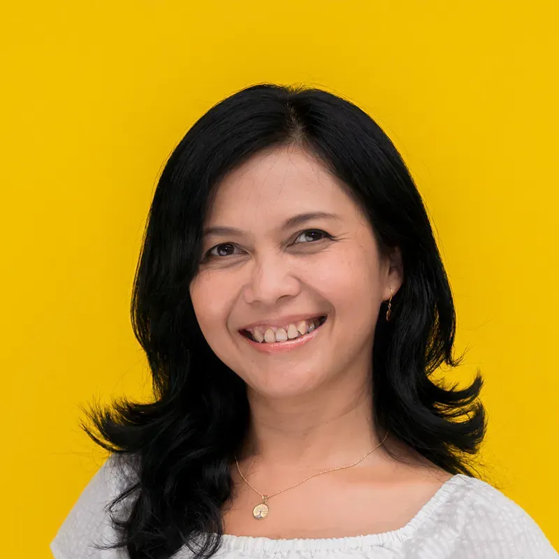 A woman wearing a white shirt and a choker is smiling for the camera.