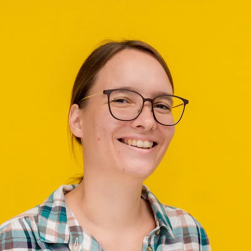 A woman wearing a blue polka dot shirt is smiling for the camera.