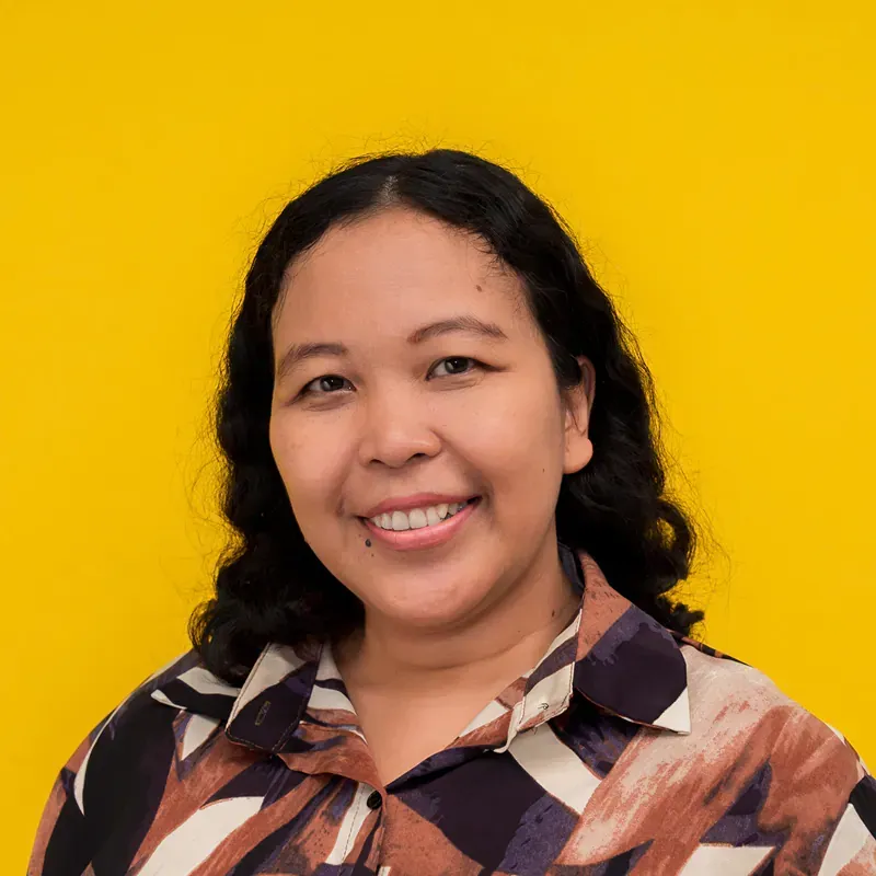 A woman is smiling and wearing a pink shirt
