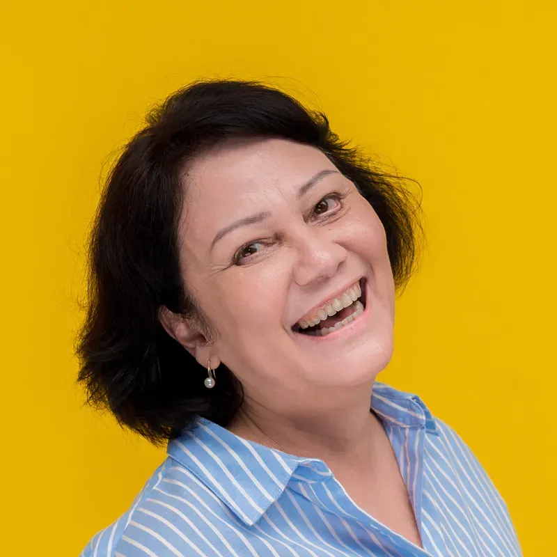 A woman wearing a blue striped shirt is smiling for the camera.