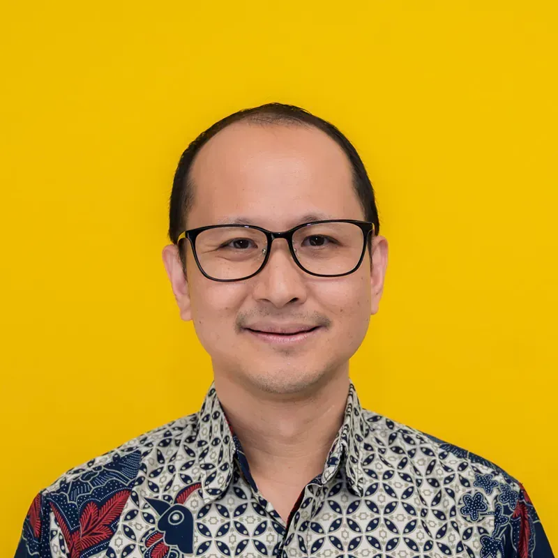 A man wearing glasses and a blue shirt is smiling for the camera.