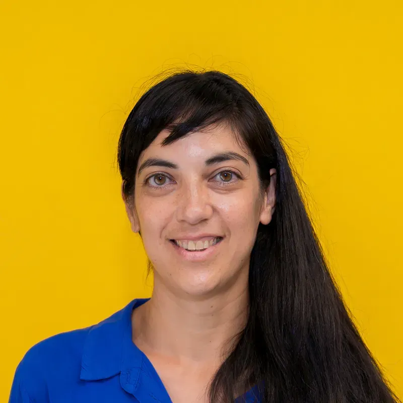 A woman in a striped shirt is standing in front of a white wall.