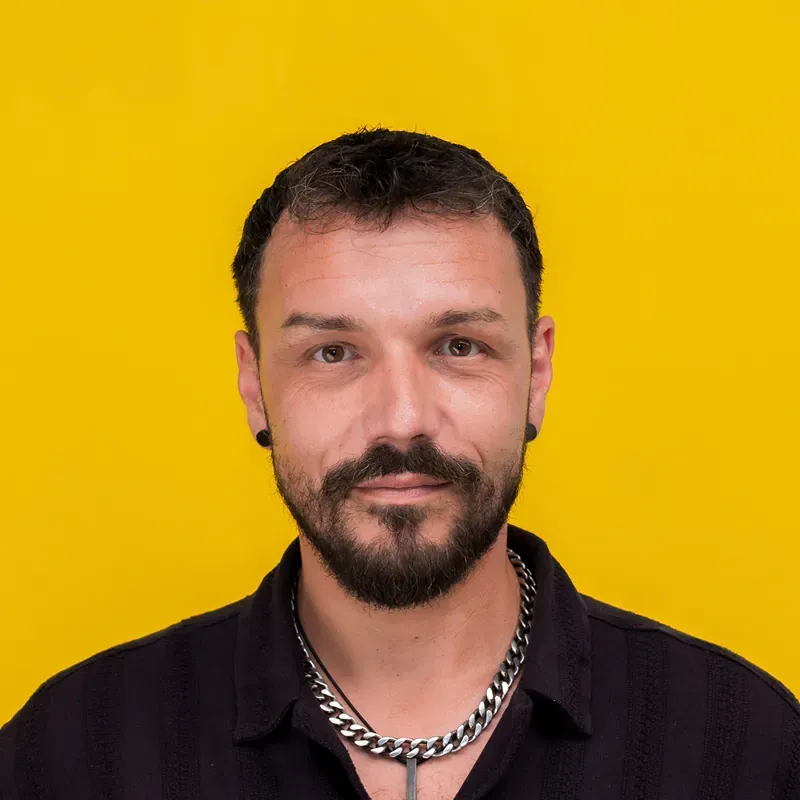 A man with gray hair is wearing a black shirt and looking at the camera.