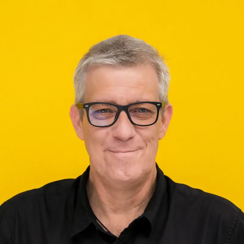 A man with gray hair is wearing a black shirt and looking at the camera.