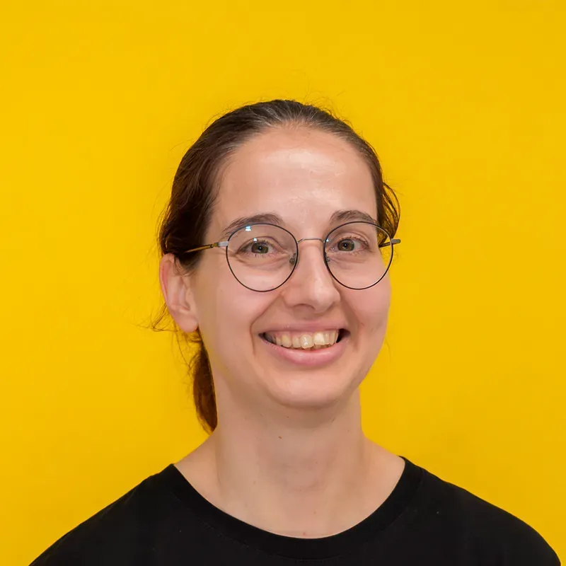 A woman with long dark hair and red lipstick is smiling for the camera.
