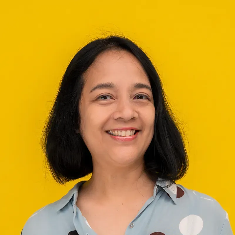 A woman is smiling for the camera and wearing a green sweater.