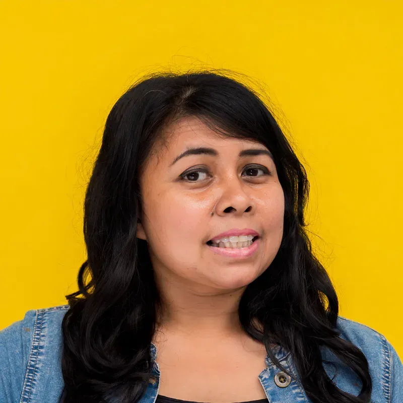 A woman is taking a selfie in front of a blue curtain.