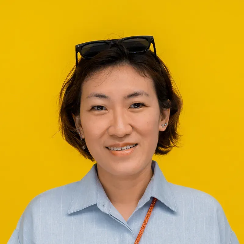 A woman is smiling for the camera and wearing a green sweater.