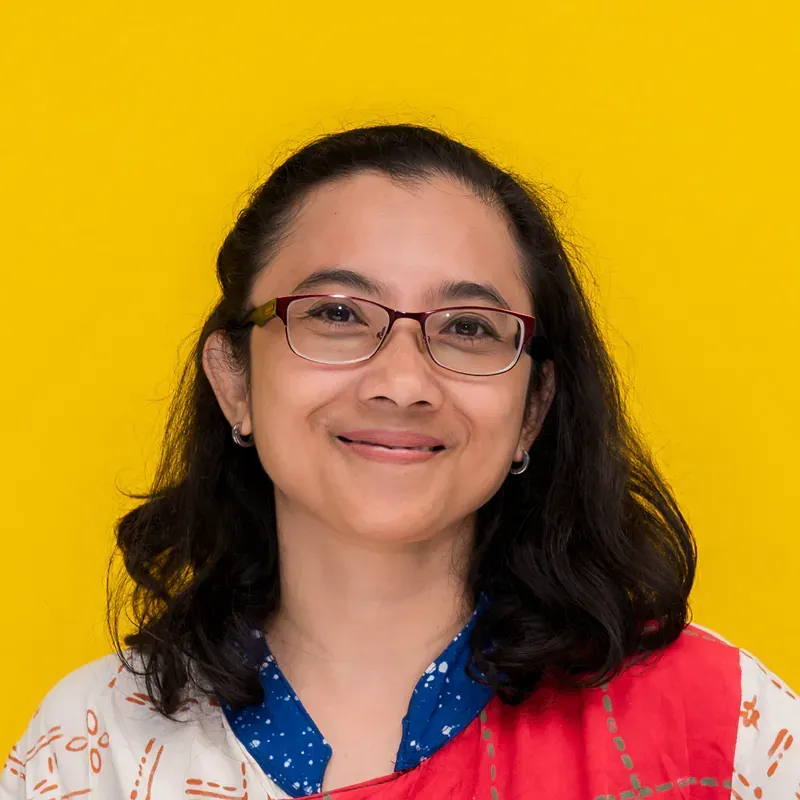 A man wearing glasses and a red shirt is smiling for the camera.