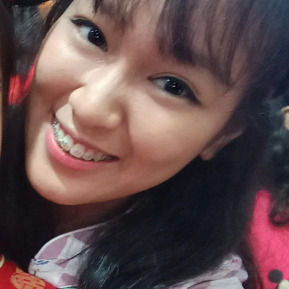 A woman with braces on her teeth smiles for the camera