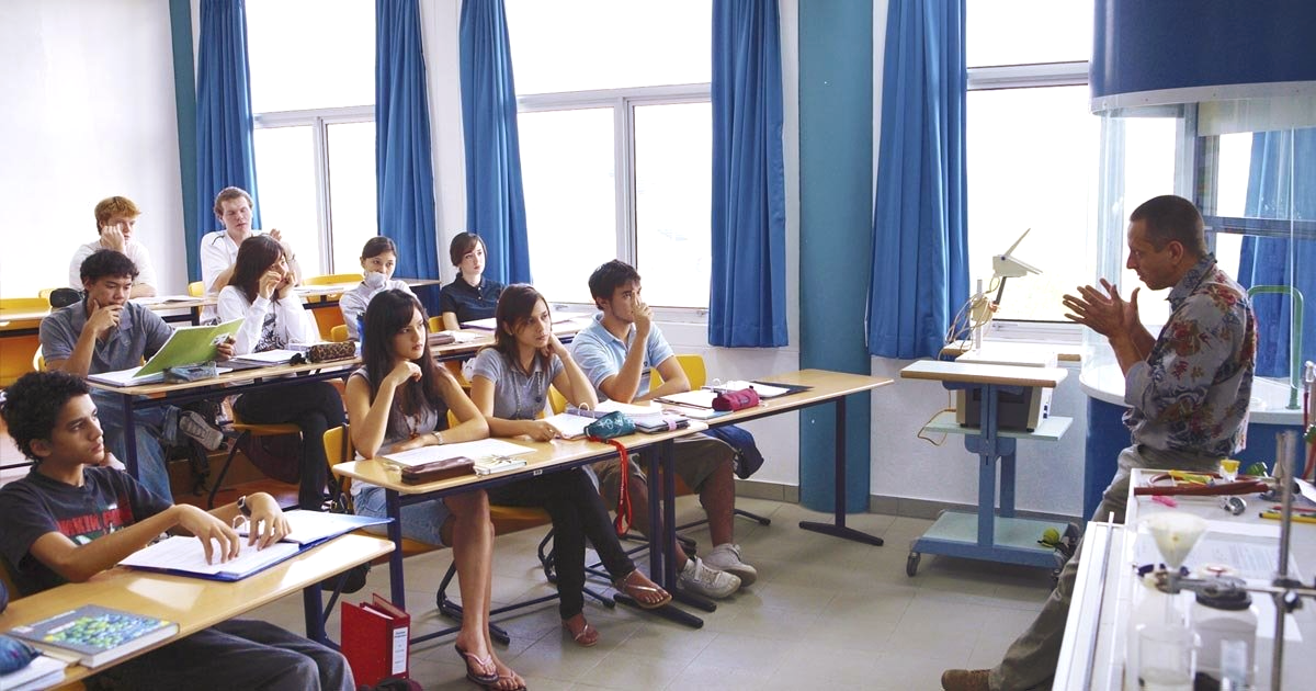 A large group of people are crossing a busy city street.