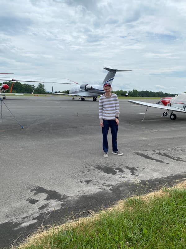 a man is standing in front of a plane on a runway .